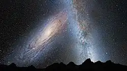 This illustration shows a stage in the predicted merger between our Milky Way galaxy and the neighboring Andromeda galaxy, as it will unfold over the next several billion years. In this image, representing Earth's night sky in 3.75 billion years, Andromeda (left) fills the field of view and begins to distort the Milky Way with tidal pull.
