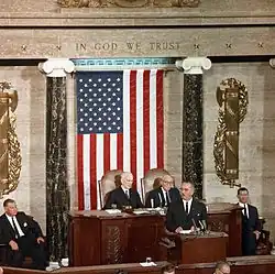 Political leaders in US with flag in background.
