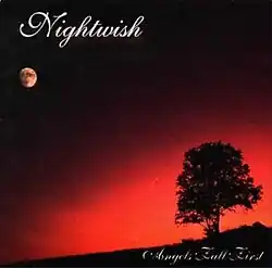 A nighttime image with a tree far in the distance and the moon above in the skyline. The sky is a dark black and the image colors fade to a bright red near the tree.