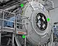 Each Active CBM has four Controller Panel Assemblies. With five ACBM's, Node 3 carried 20 such units to orbit. As seen here on an axial ACBM (1) CPA's are cantilevered across the hatch. In this photo taken at KSC in 2009, the proximity of M/D petals to the CPA is also visible on a radial port (2). Another port (3) has already been equipped with the M/D Center Section.[6][122]